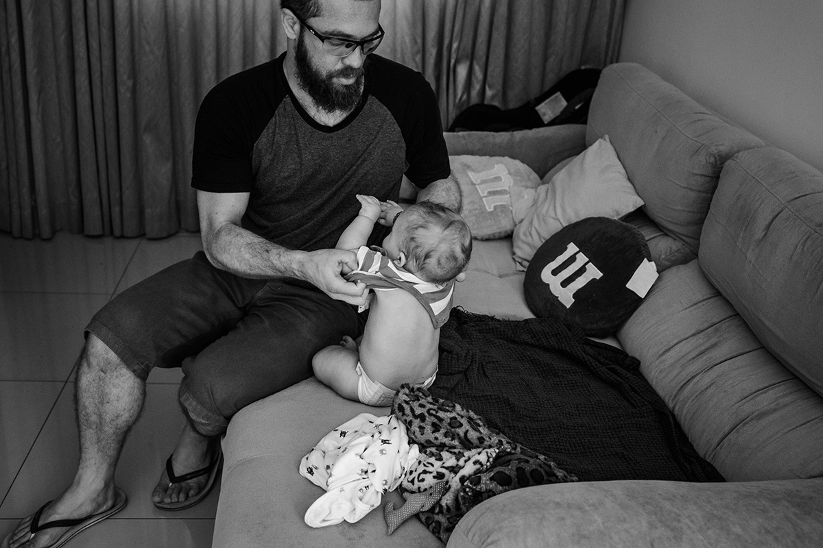 pai tirando a roupa do bebê para o banho