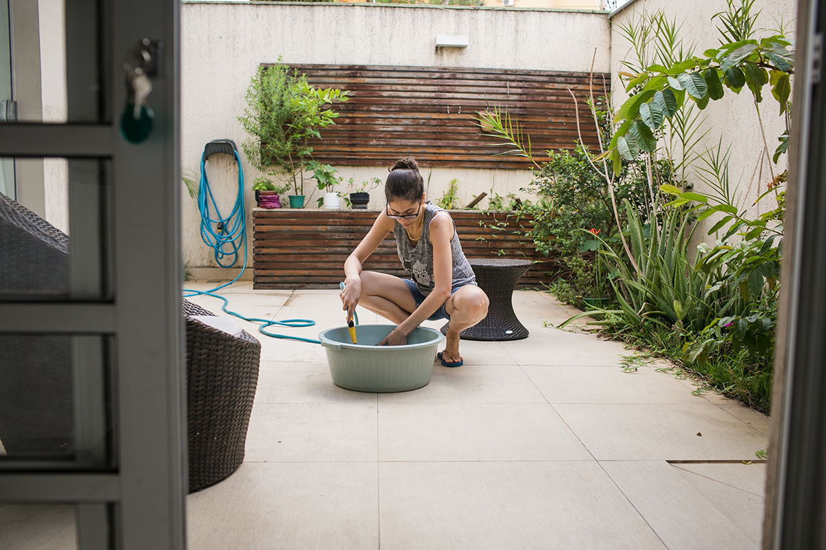 mãe preparando a bacia no quintal da casa para dar banho no seu bebê