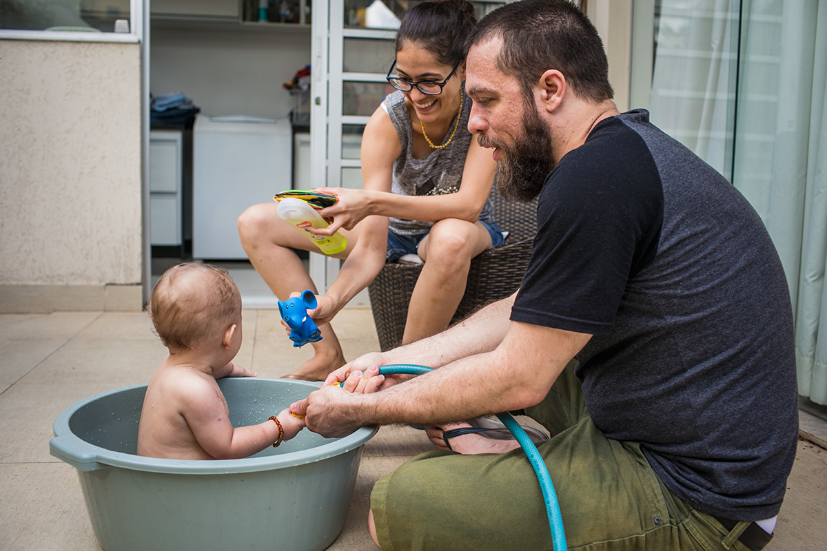 Adriana Costa fotografou os pais com seu bebê no quintal, na hora do banho