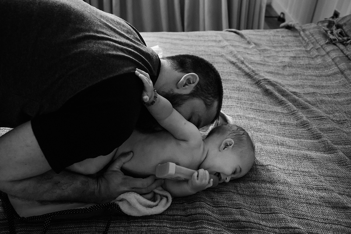 pai fazendo cócegas no filho ao enxugá-lo após o banho