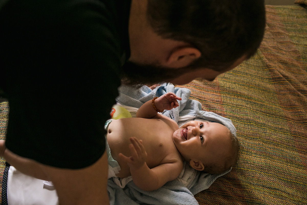 bebê sorrindo para o pai que cuida dele, por Adriana Costa