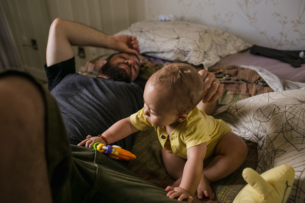 pai quase dormindo enquanto bebê brinca