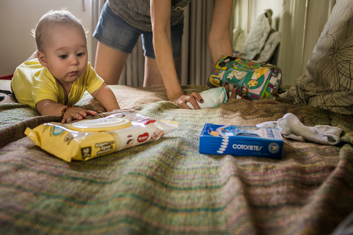 Foto de Adriana Costa do bebê de bruços tentando pegar objetos na cama