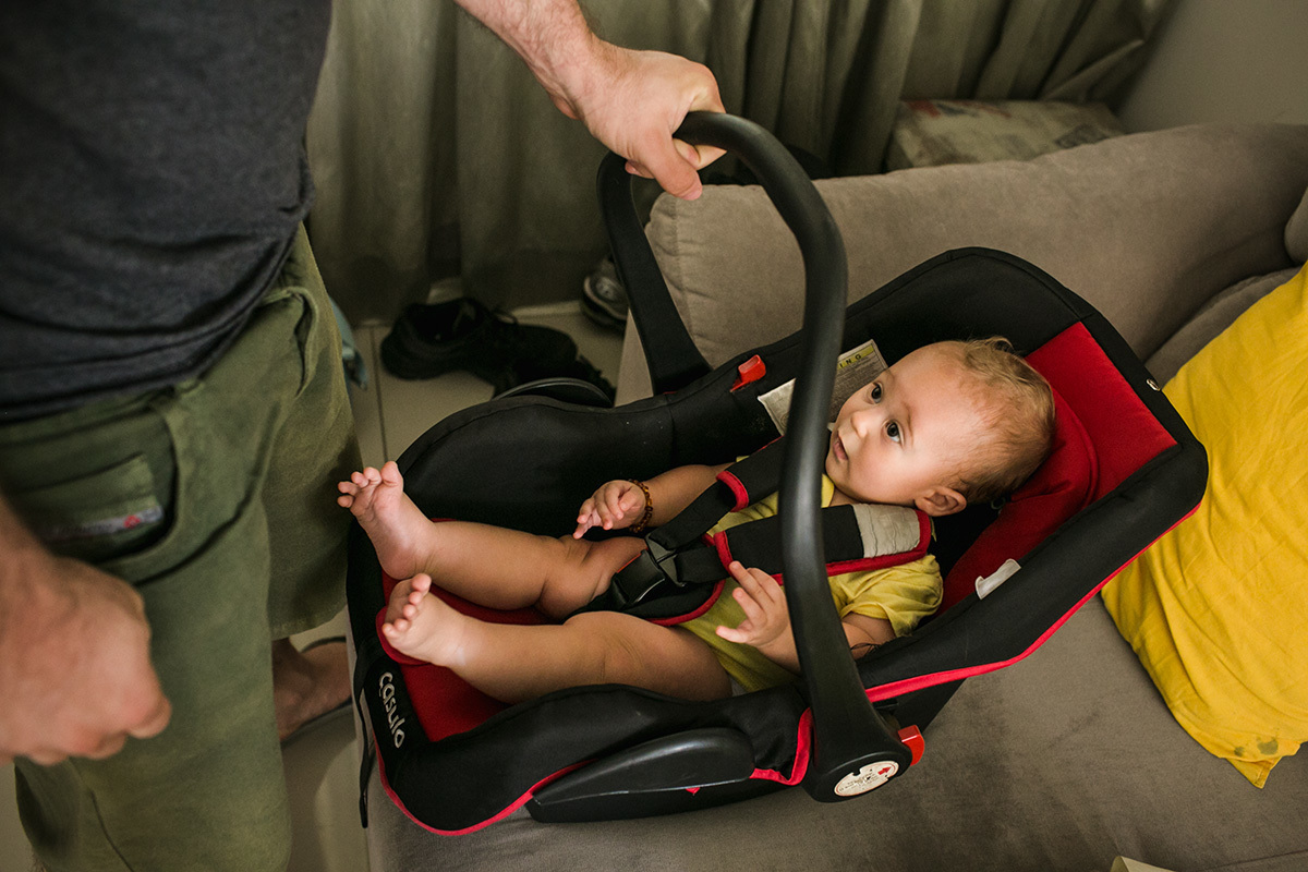 pai coloca seu bebê na cadeirinha para carros