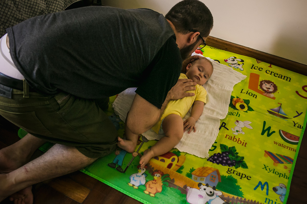 pai colocando seu bebê no colchão com todo o cuidado para não acordá-lo, por adrianacostafotos