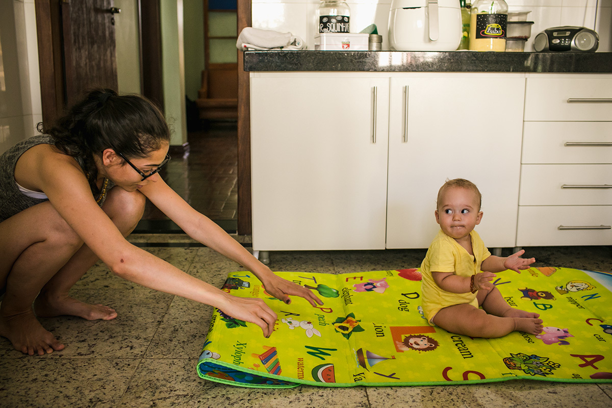 bebê olhando de forma engraçada para a mãe que puxa o seu tapete