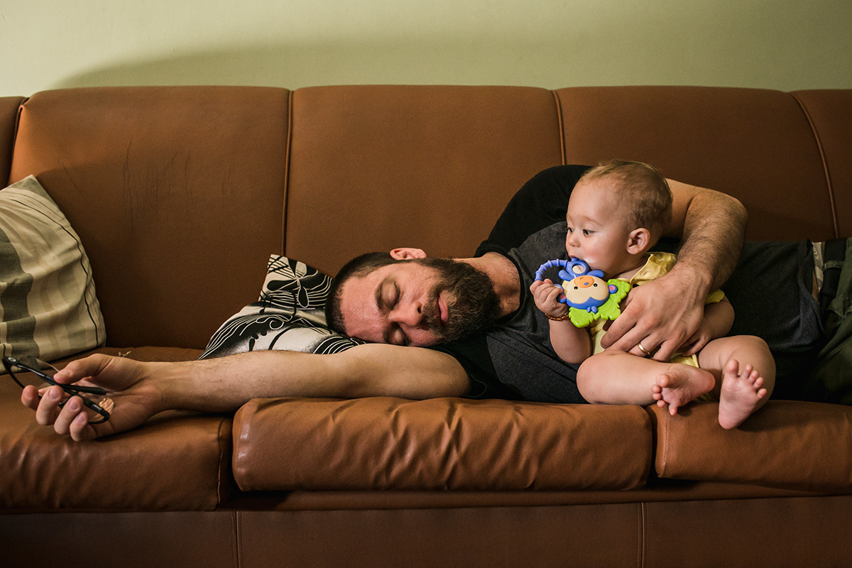 pai cochilando com seu bebê ao lado o olhando, por adrianacostafotos