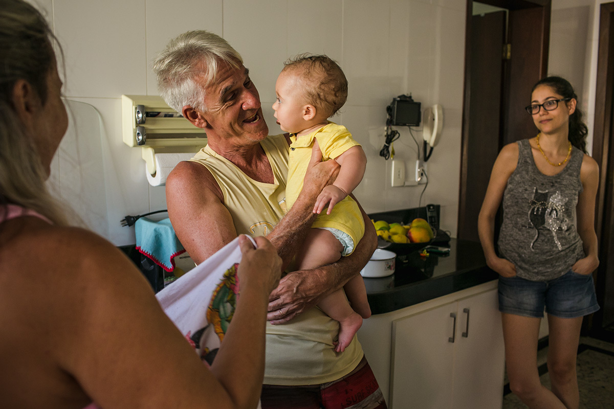 mãe observando feliz avós com o seu filho na cozinha da casa