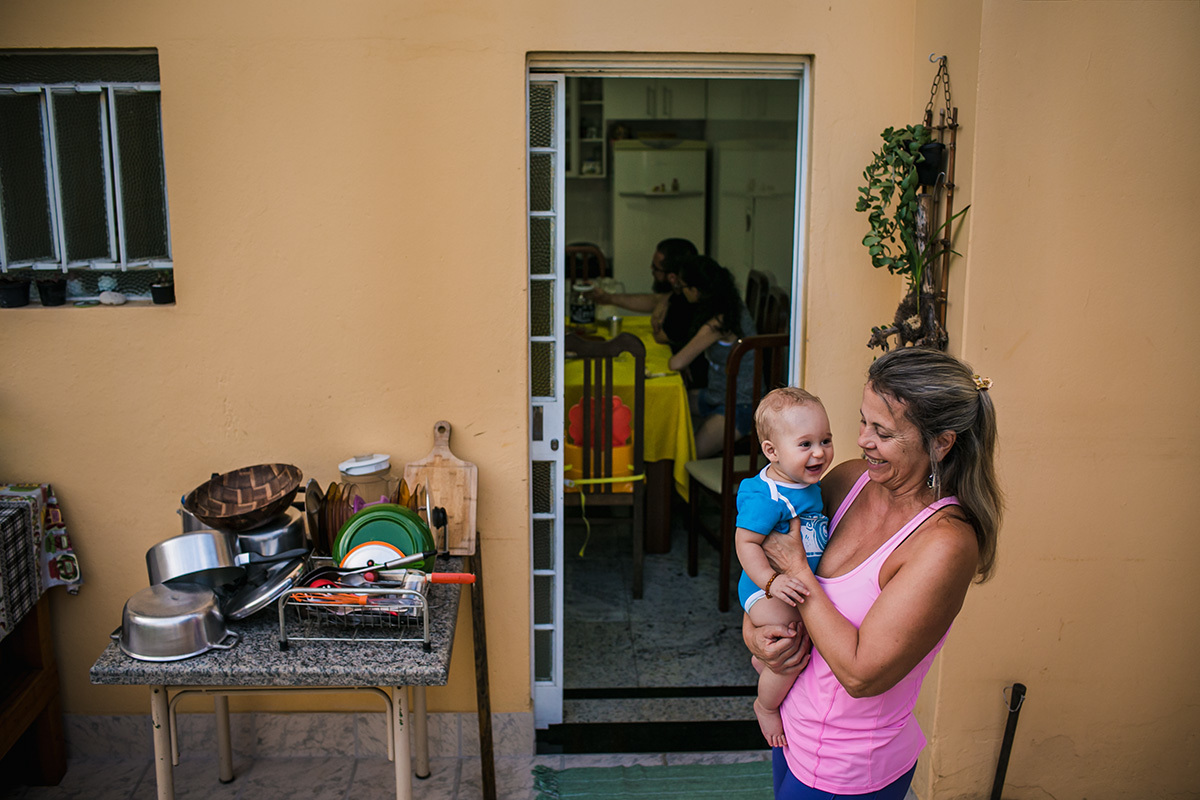 avó com o seu neto no quintal da casa enquanto os pais fazem um lanche na cozinha, por adrianacostafotos