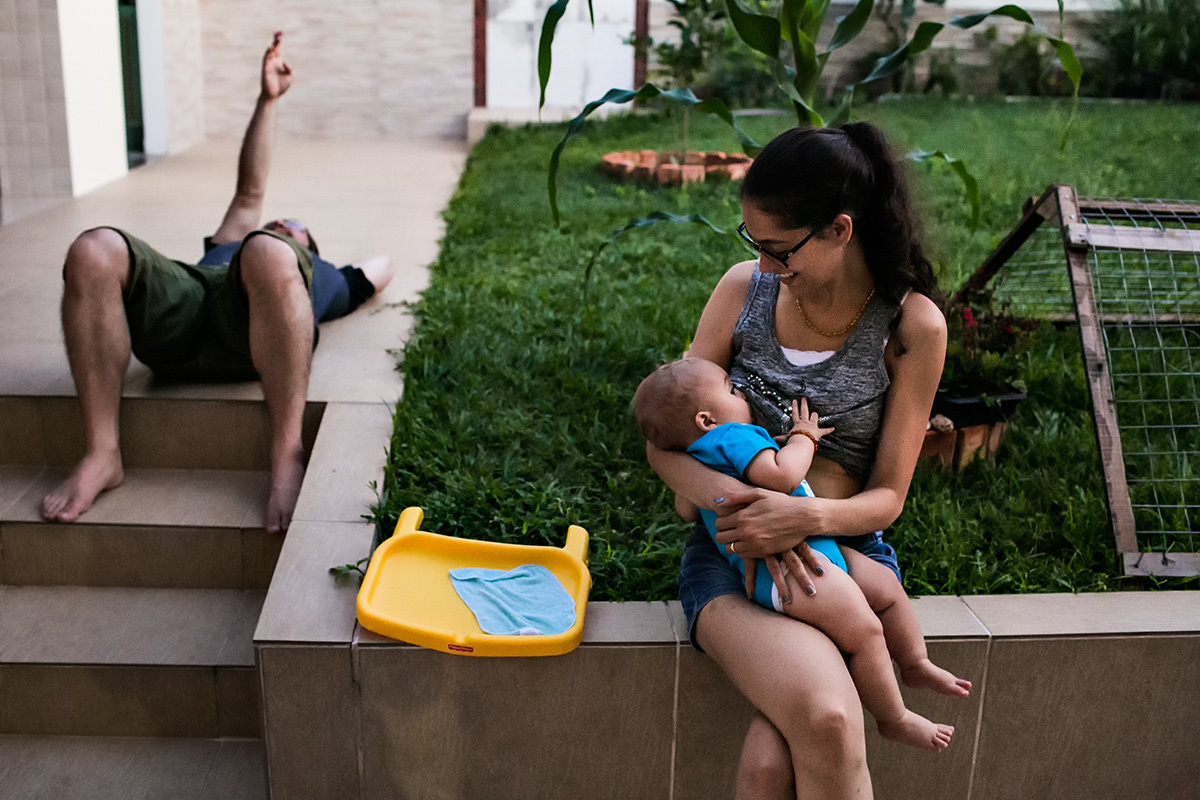 mãe amamentando seu bebê no quintal da casa da avó enquanto o pai observa o céu ao seu lado, por adrianacostafotos