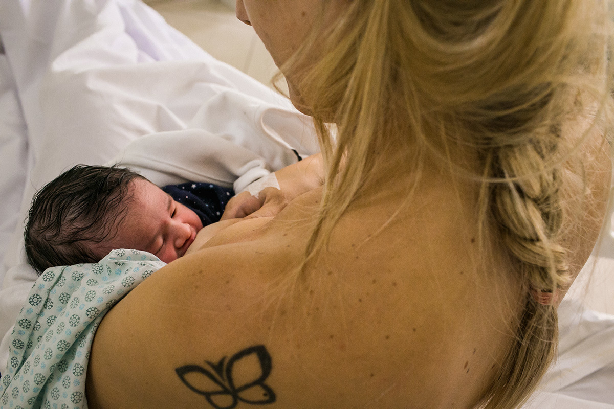mãe na maternidade amamentando sua filha pela primeira vez  em foto de Adriana Costa