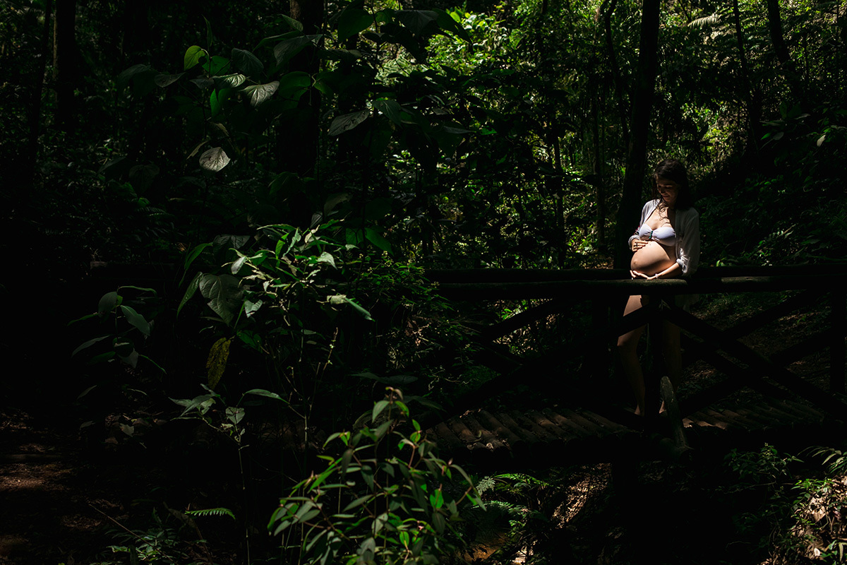gestante em um ponto de luz no meio de uma mata de natureza linda
