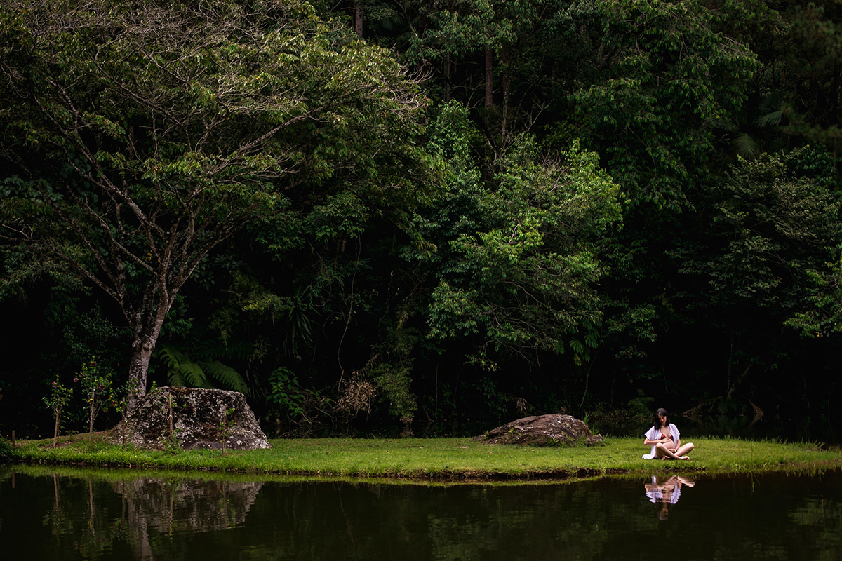 gestante meditando numa pequena ilha rodeada por árvores em foto de Adriana Costa