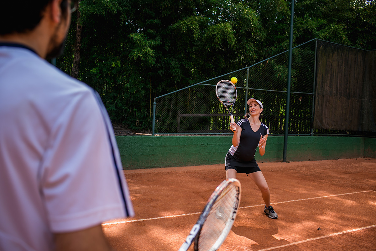 mulher grávida jogando tênis com seu marido, por Adriana Costa