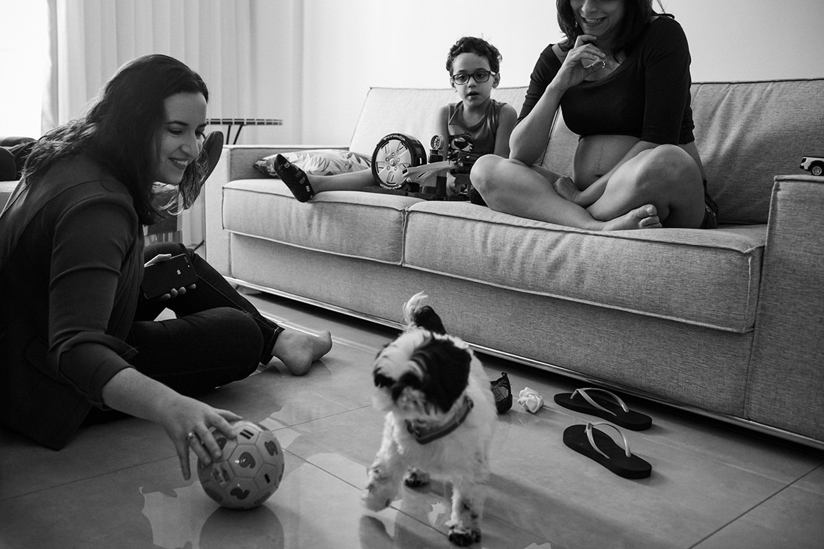 família reunida brincando de bola com a cachorrinha da casa