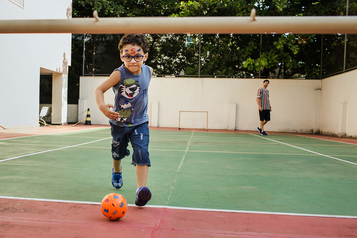 criança fantasiado jogando bola 