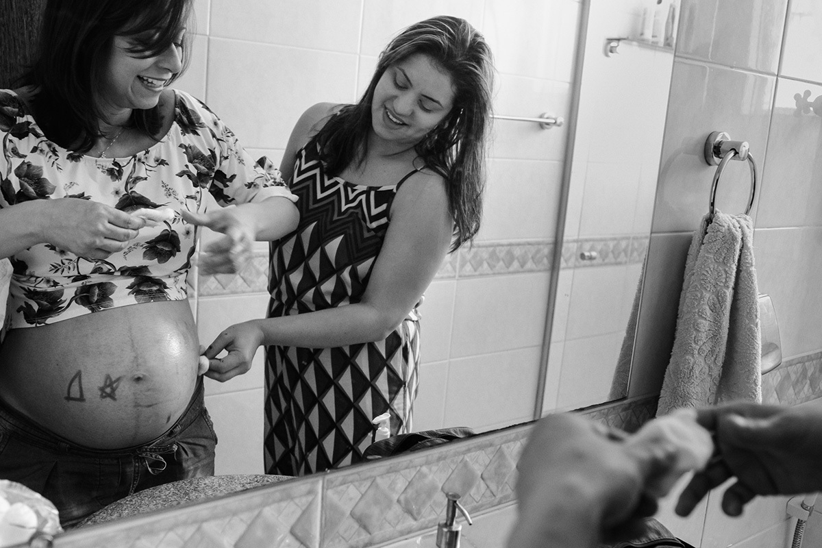 cunhada ajudando a gestante a limpar a barriga que o sobrinho desenhou com batom