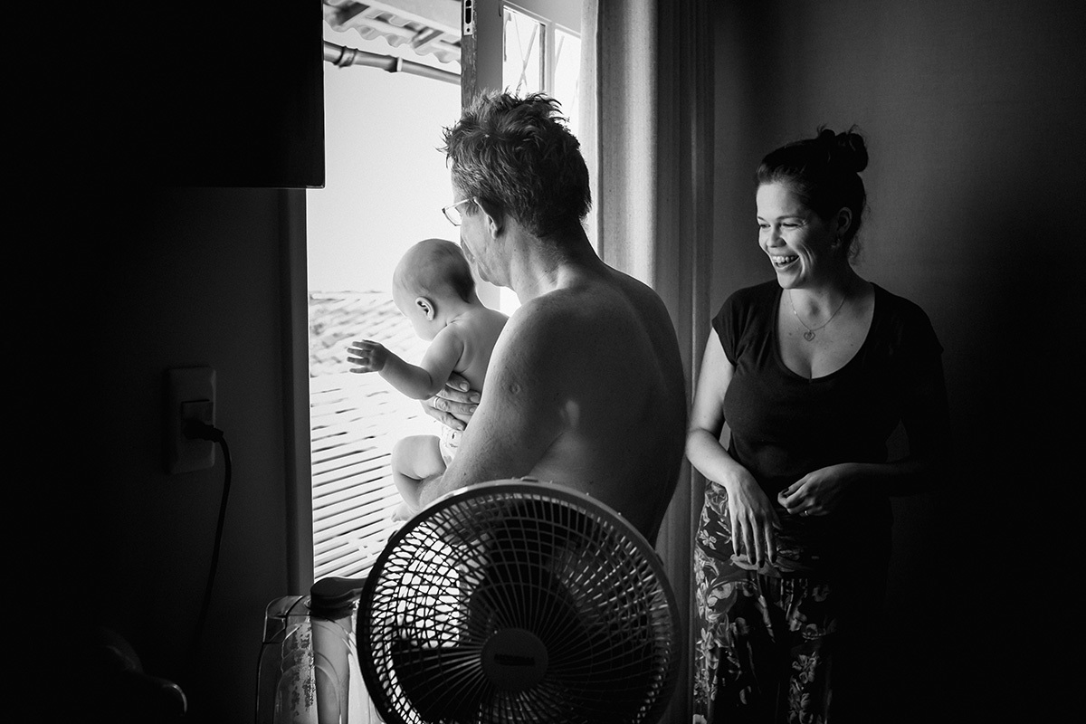 pai e mãe levando o bebê para a varanda para o banho de sol