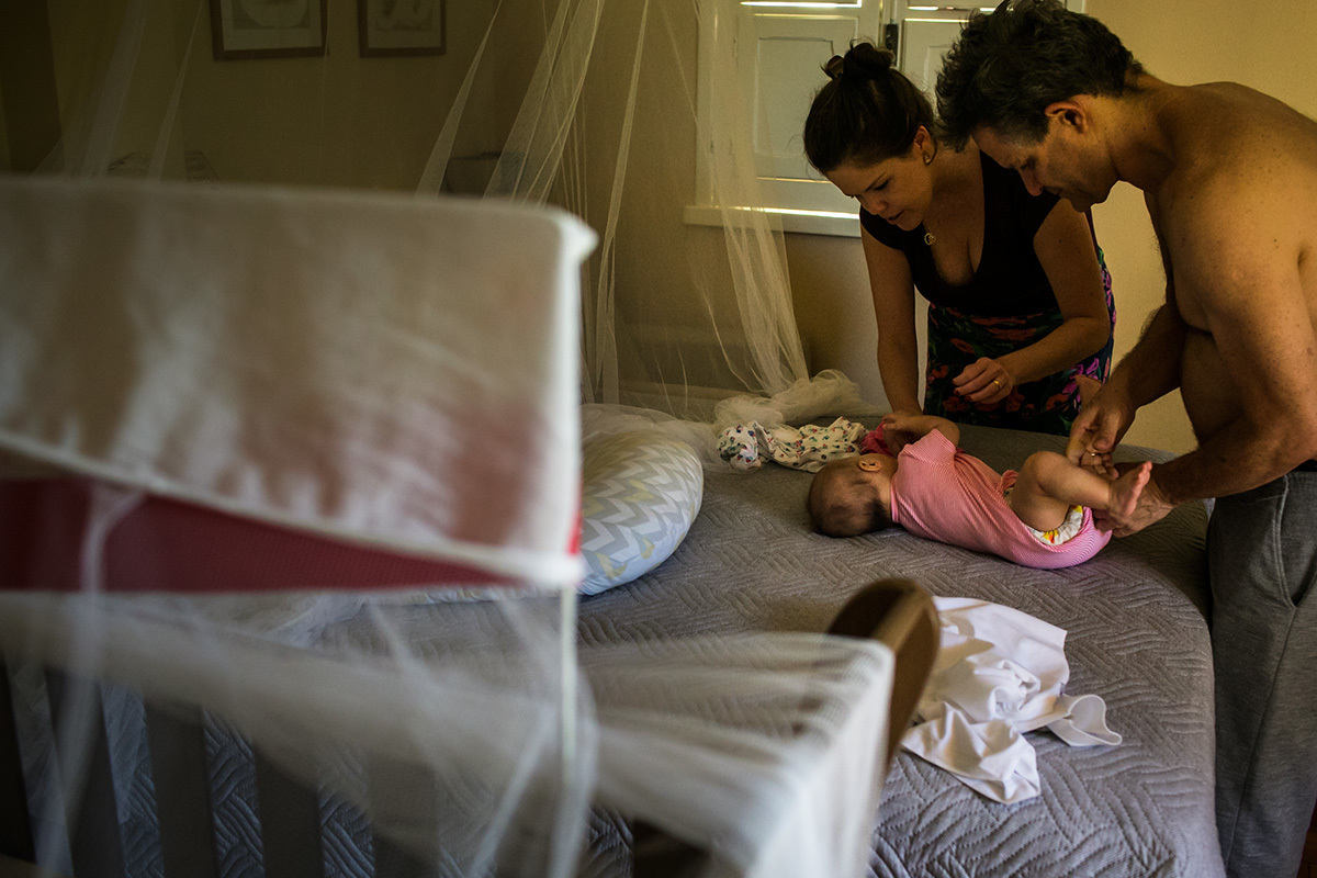 pais trocando a roupa da filha de cinco meses