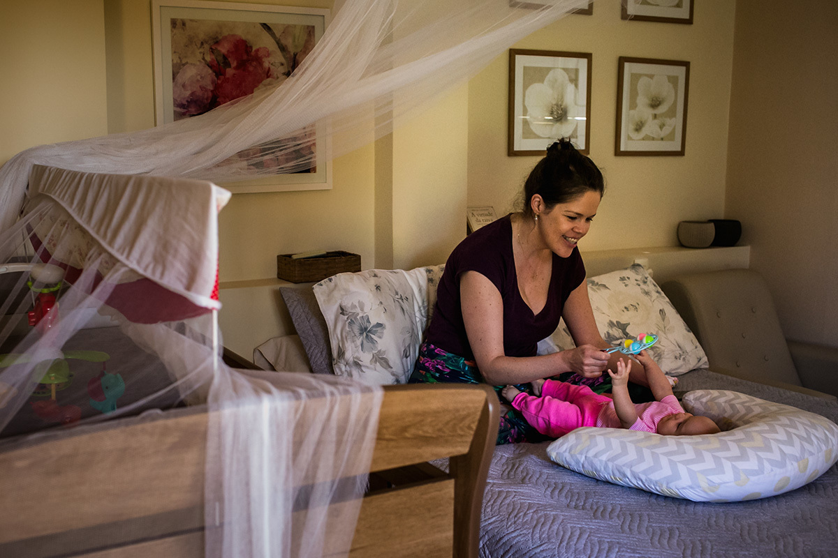 mãe dando o chocalho para o seu bebê brincar 