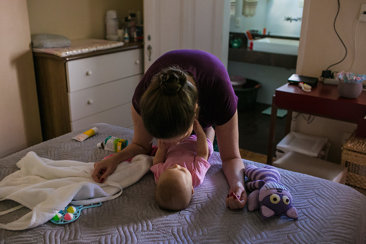 mãe em momento de cuidado com sua bebê