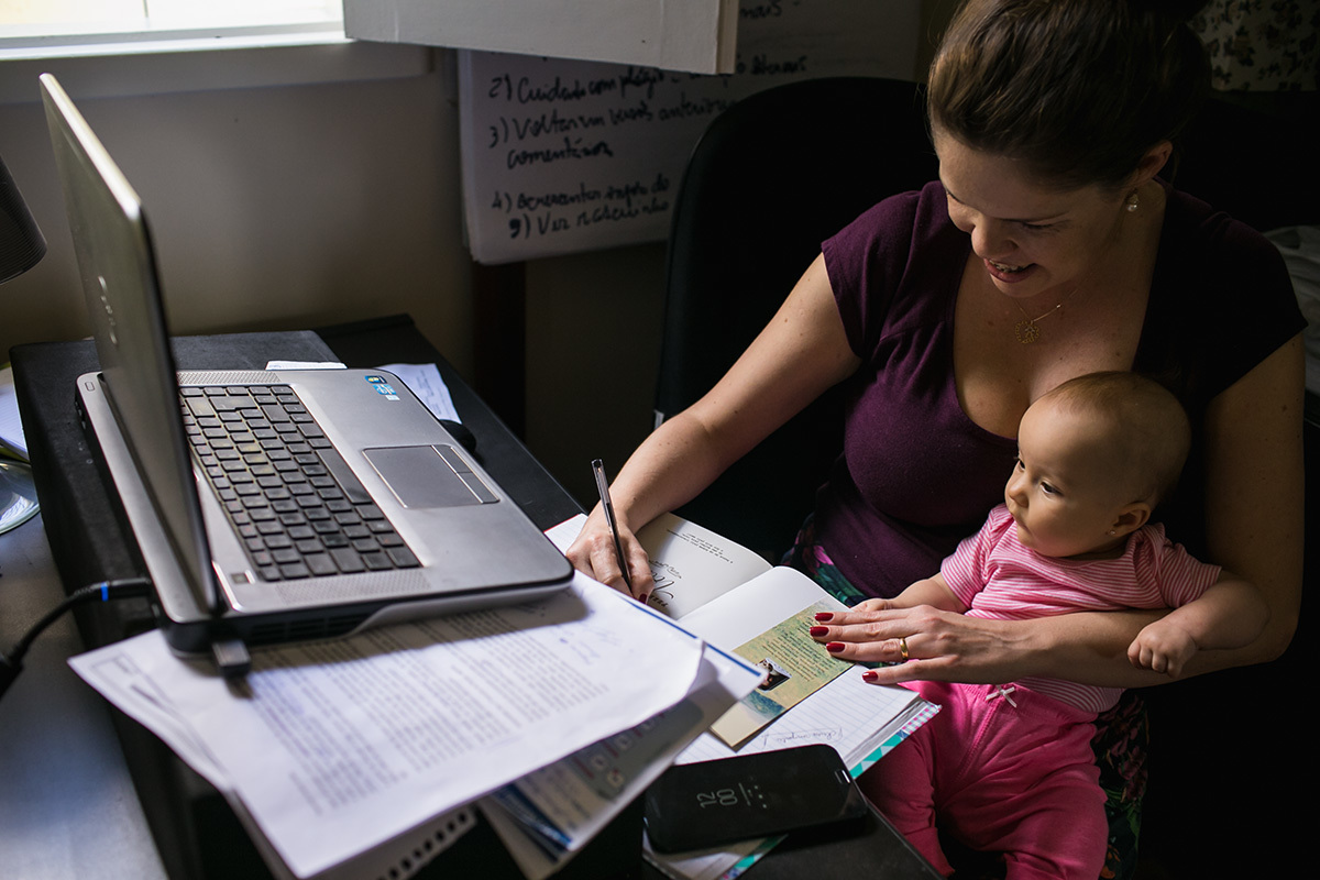 foto de Adriana Costa da mãe trabalhando com sua bebê no colo