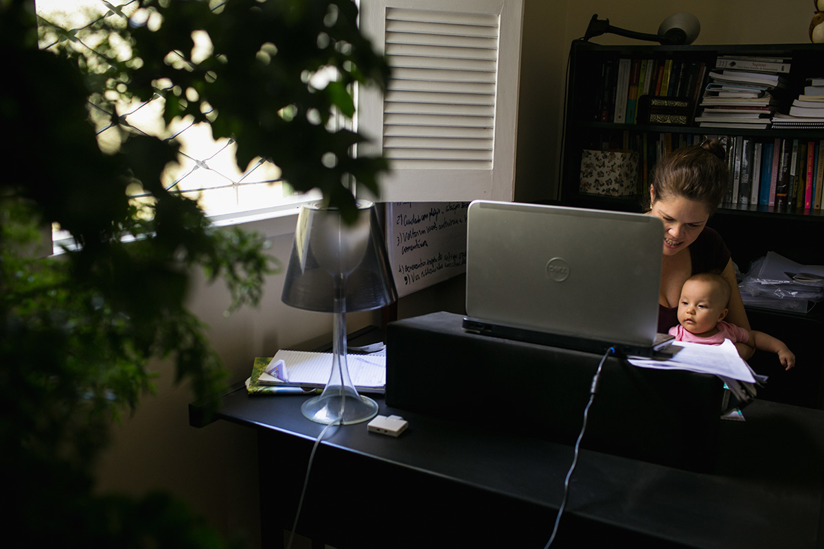 registro documental feito por Adriana Costa da mãe trabalhando com sua bebê ao colo