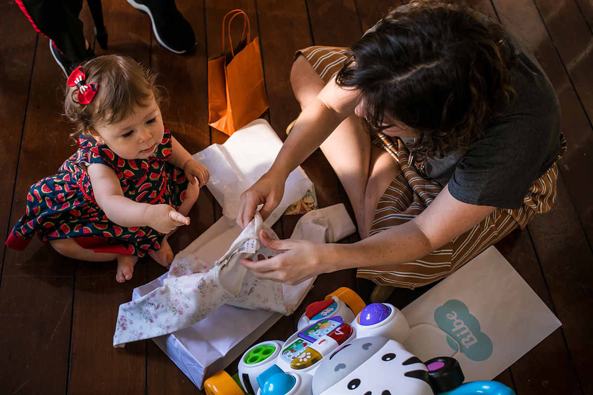 mãe e sua bebê de um ano abrindo os presentes do aniversário de um ano, em foto de Adriana Costa