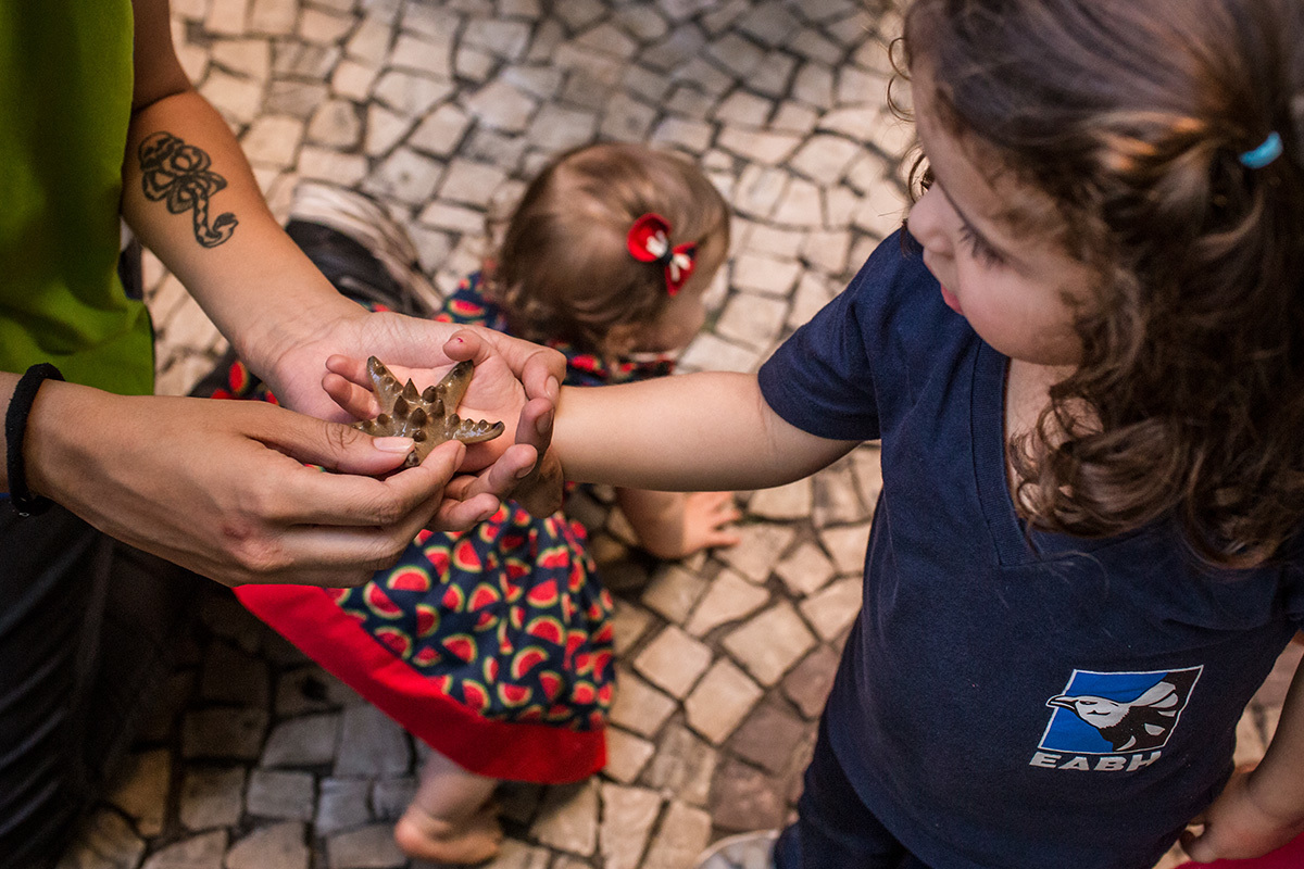 criança sentindo na mão uma estrela marinha