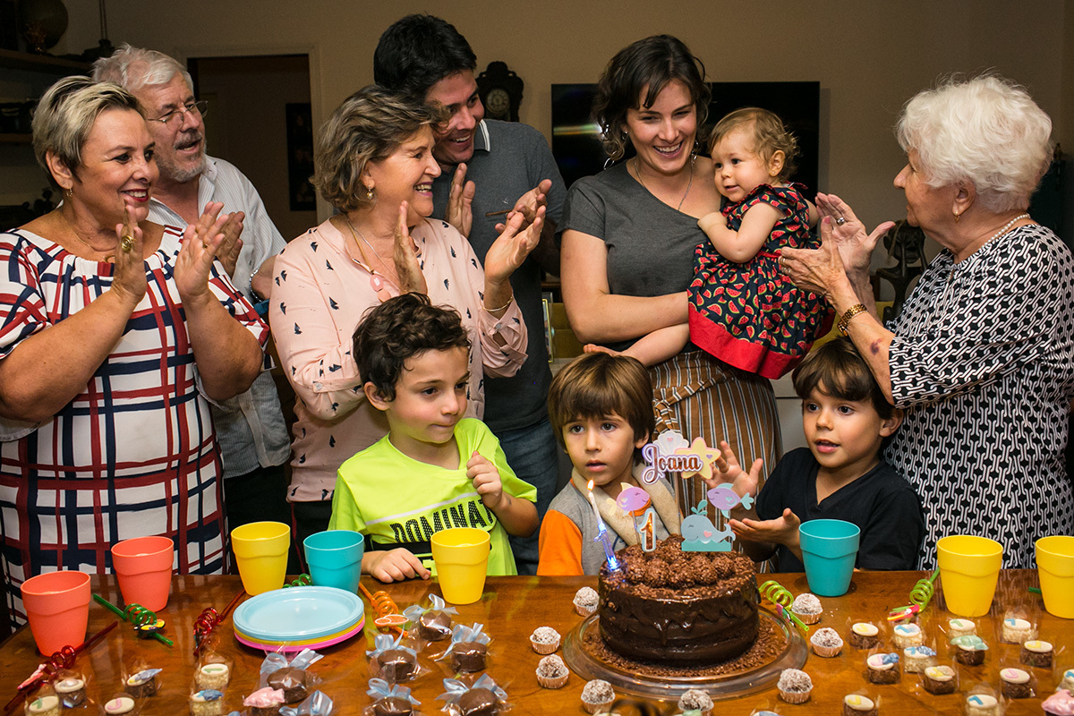 bebê de um ano cantando parabéns junto a família e amigos