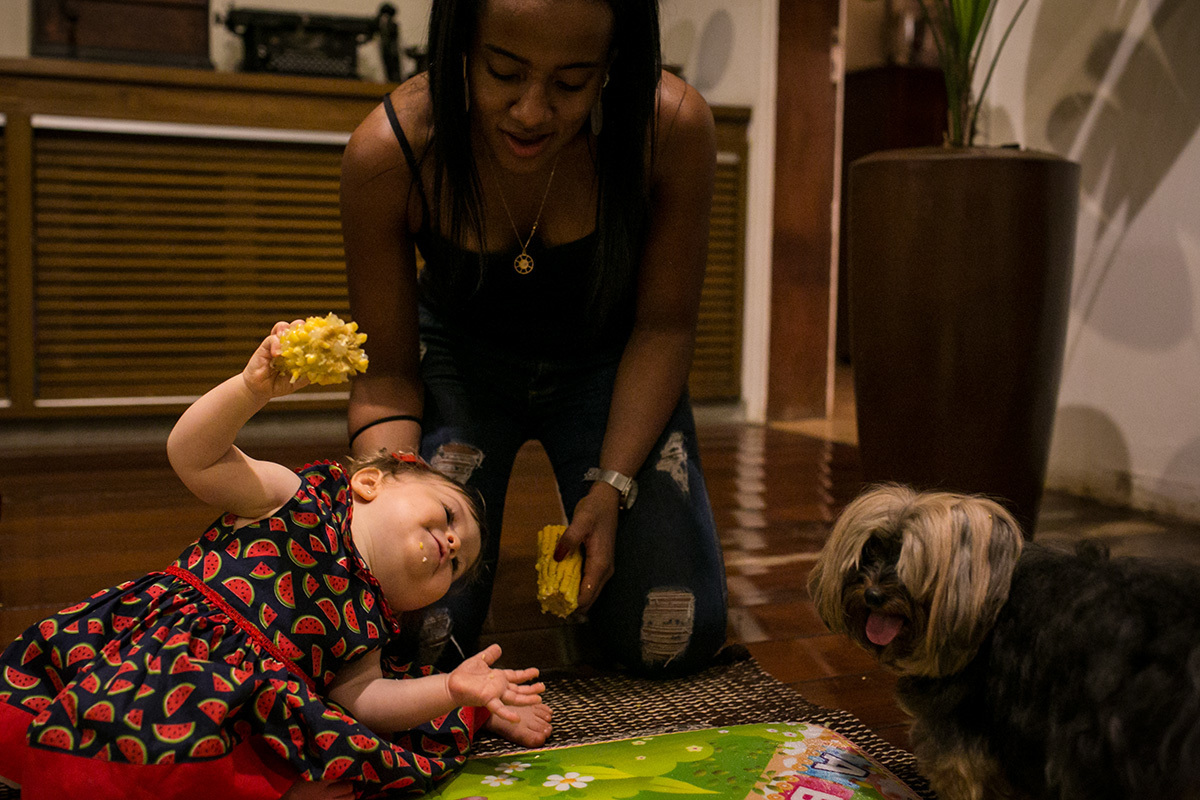criança comendo milho e brincando com o cachorro