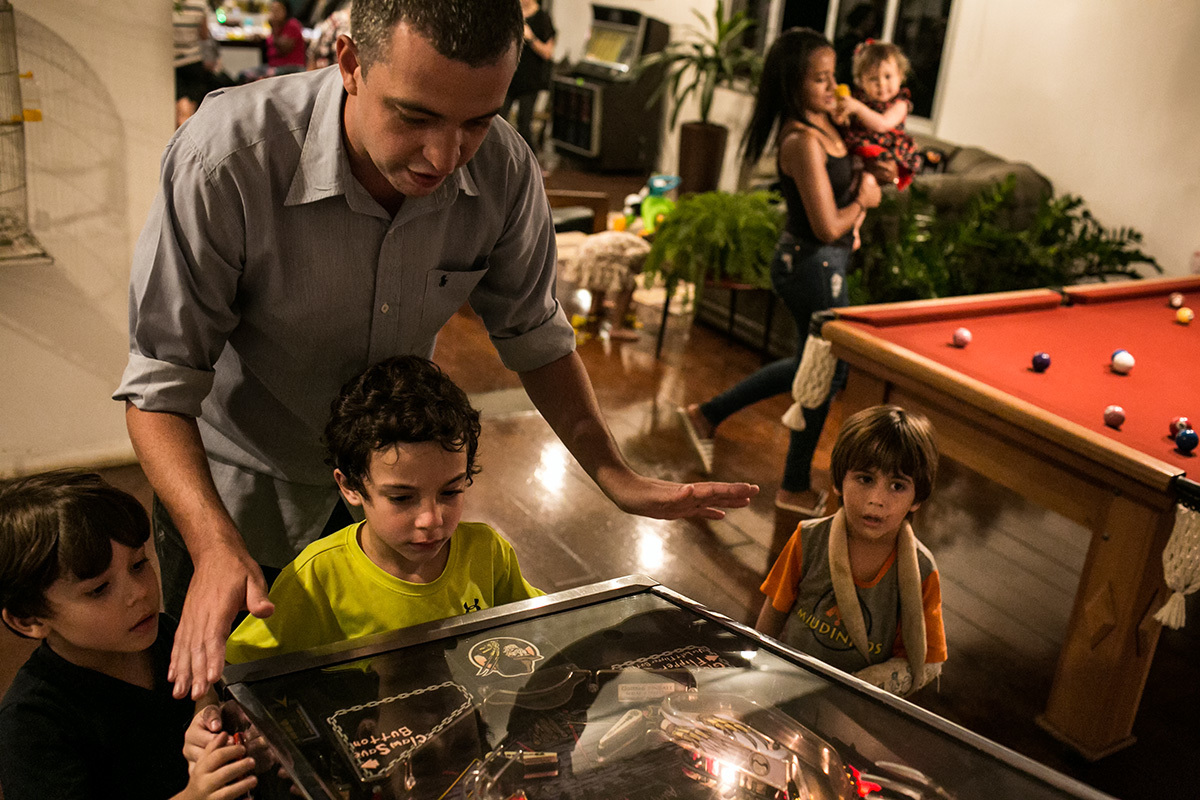 crianças e adultos brincando de fliperama em um aniversário caseiro