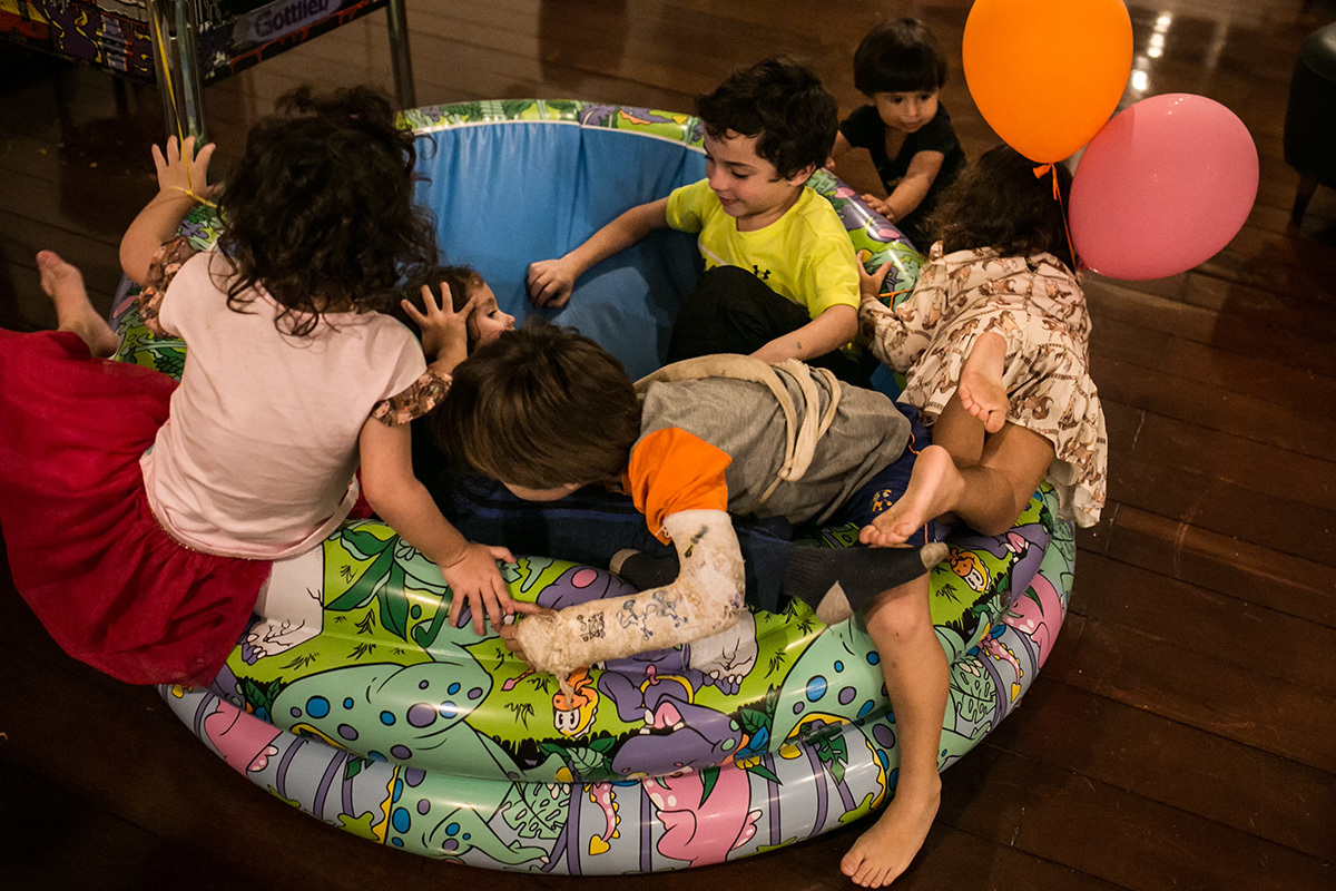 Crianças colocando a piscina de bolinha de cabeça para baixo para pular como trampolim, em foto de Adriana Costa