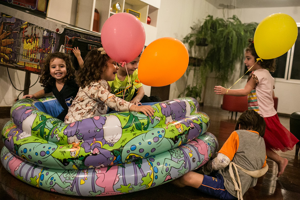 Crianças se divertindo muito dando outro uso a uma piscina de bolinhas, em registro de Adriana Costa