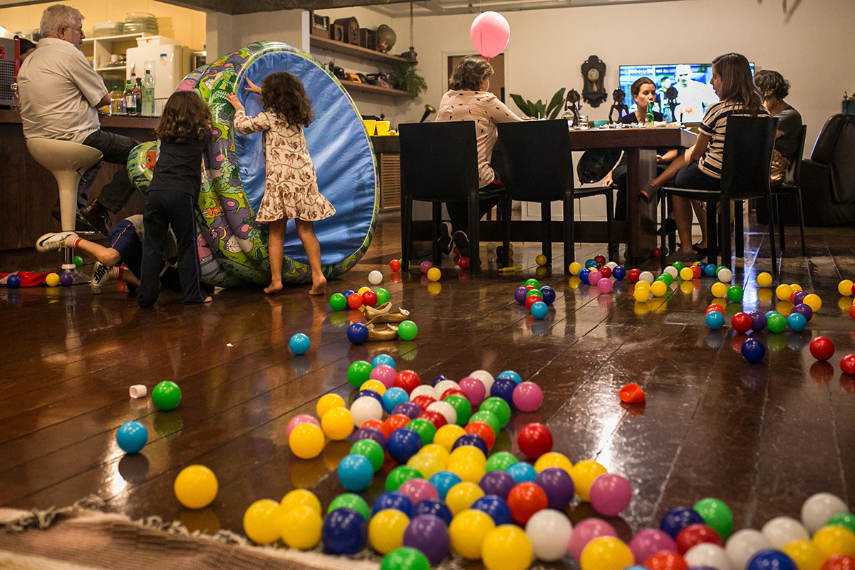 Crianças brincando em um aniversário de uma nova maneira com uma piscina de bolinhas, sem as bolinhas que ficaram espalhadas pelo chão, em foto de adrianacostafotos