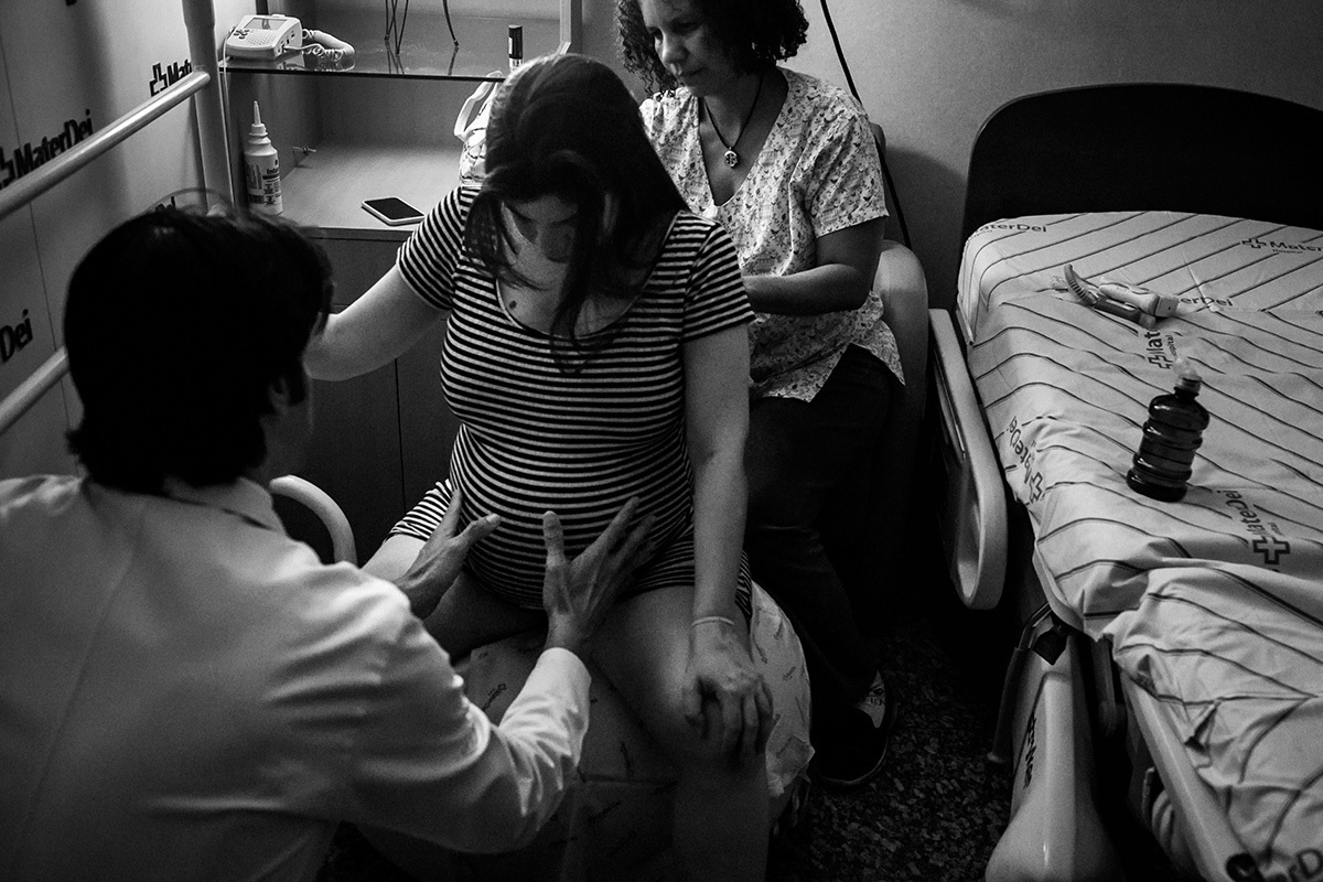 Adriana Costa fotografou médico obstetra e doula auxiliando a gestante no momento de contração