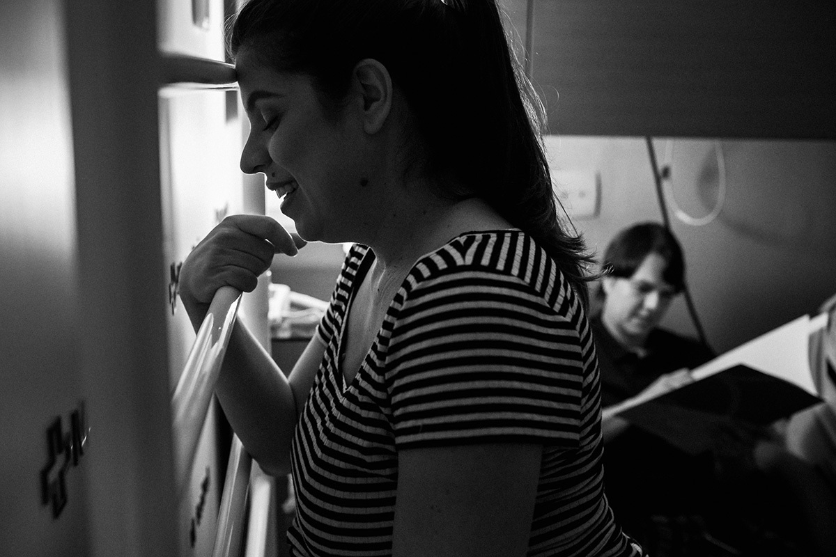 gestante sorrindo aliviadas após contração do trabalho de parto enquanto seu marido lê seu plano de parto