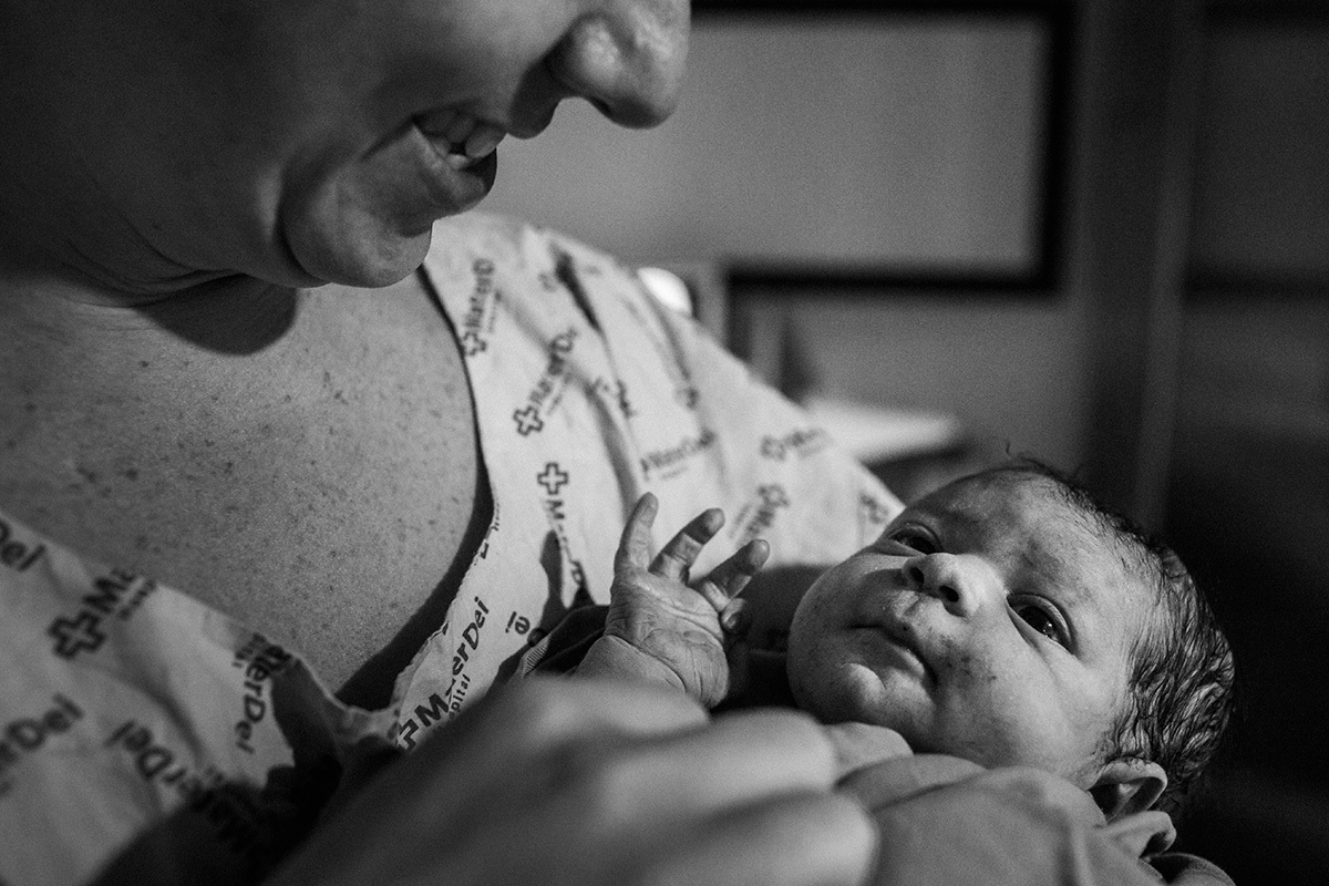 pai observa orgulhos seu filho que acabou de nascer