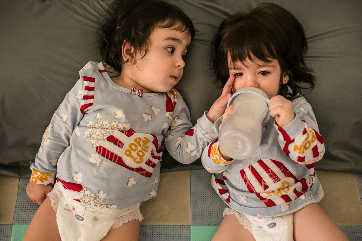 Adriana Costa fotografou as meninas dos trigêmeos brincando enquanto tomam mamadeira