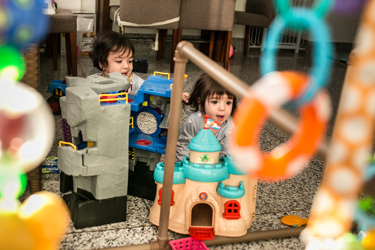 bebê puxa o cabelo de sua irmã gêmea enquanto brinca, por Adriana Costa