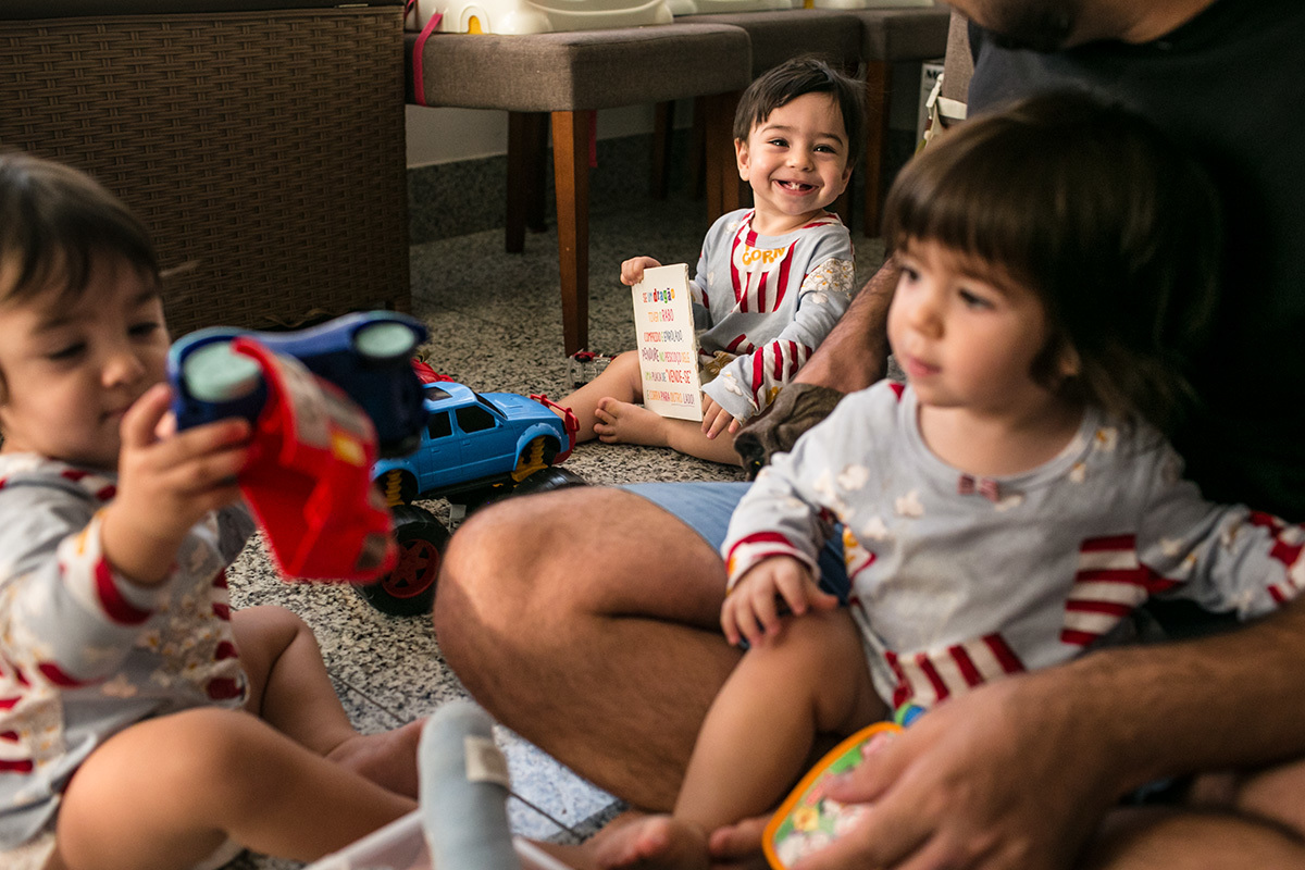 trigêmeos felizes em momento de brincadeira com o pai