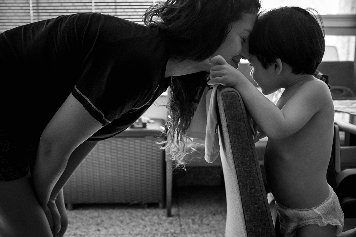 Renata Lucena faz carinho em seu filho Rafinha enquanto os trigêmeos dormem, numa foto de Adriana Costa