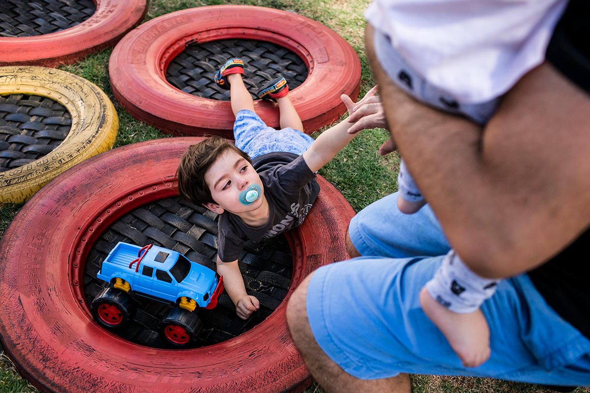 Adriana Costa documentou pai com um de seus trigêmeos no colo dando a mão ao seu filho mais velho para se levantar do chão após uma birra
