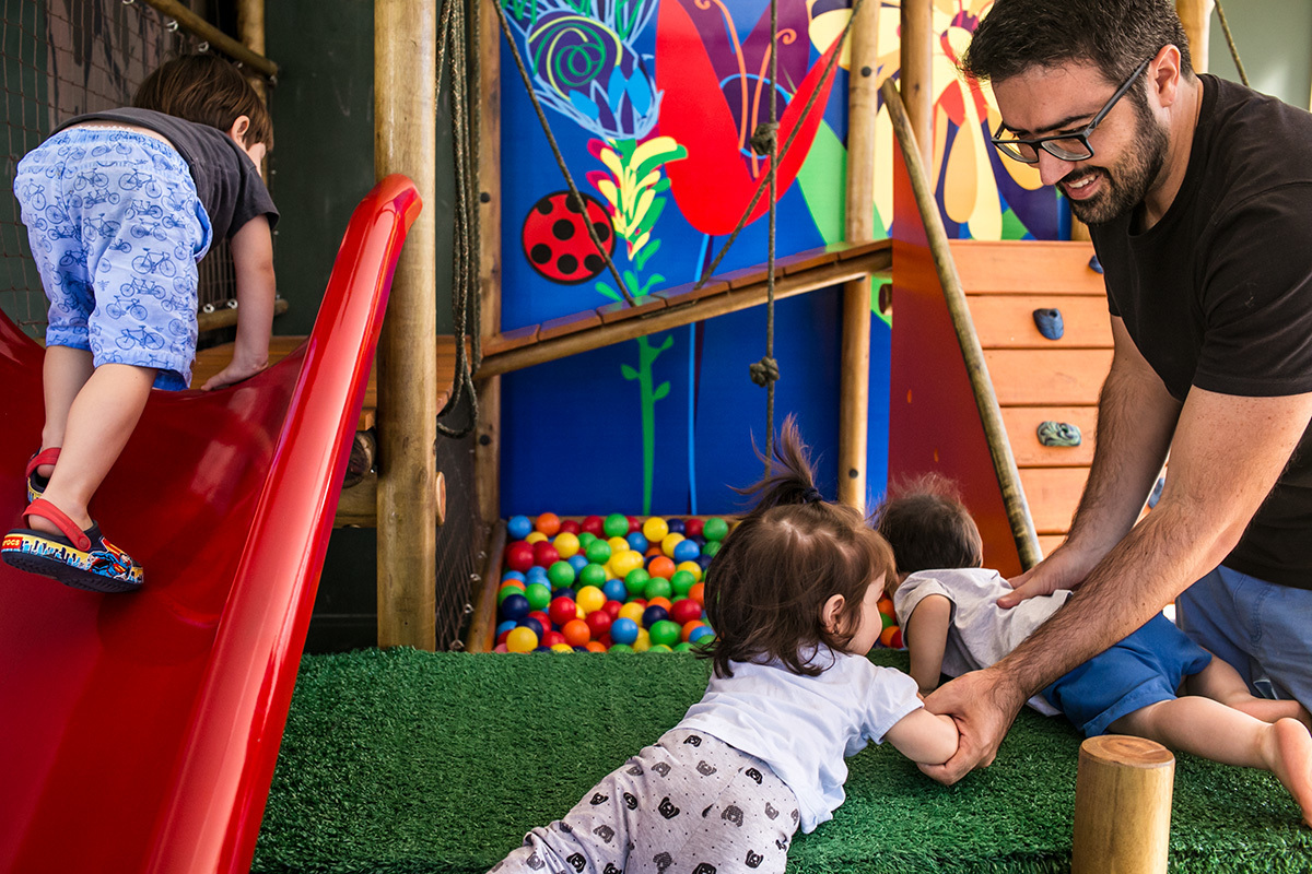 Fotografia documental de Adriana Costa do marido de Renata Lucena brincando com Rafinha e os Trigêmeos