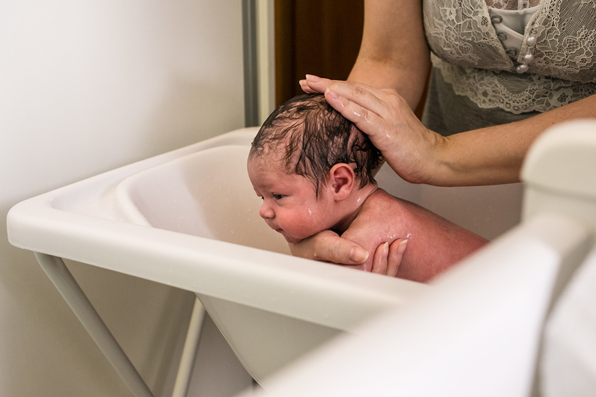 mãe dando banho em seu bebê recém-nascido
