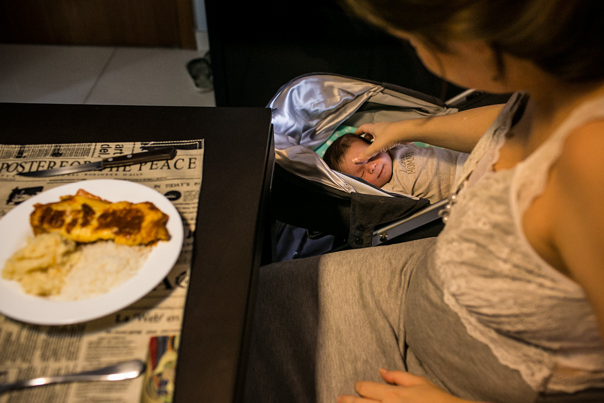 Adriana Costa fotografou mãe fazendo carinho em seu bebê que está no carrinho enquanto almoça
