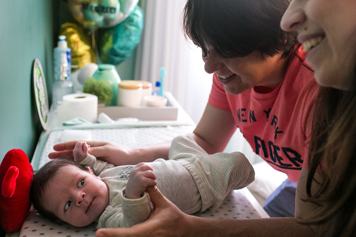 bebê olha para seus pais que sorriem para ele encantados