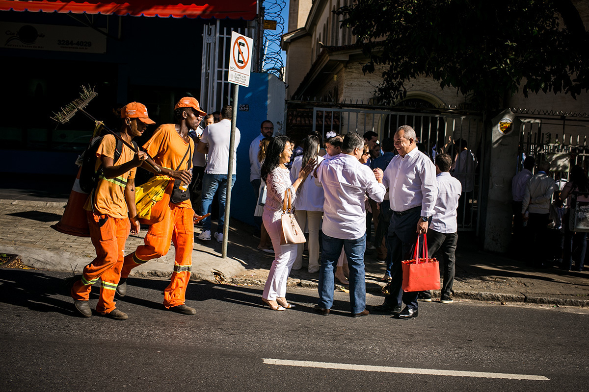 família chegando na Igreja para o batizado no momento em que os lixeiros passam, em foto de Adriana Costa