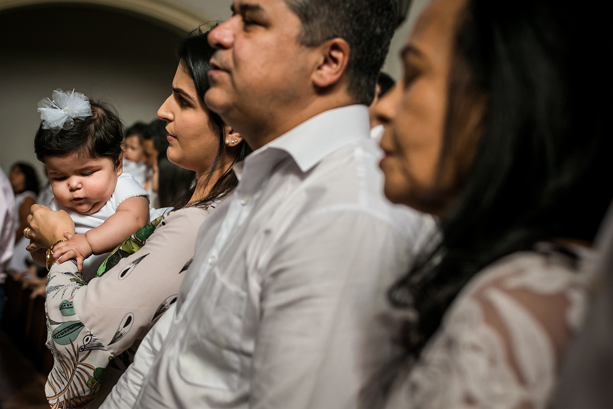 bebê brincando com a mão da mãe enquanto ela reza na cerimônia de batismo, por adrianacostafotos