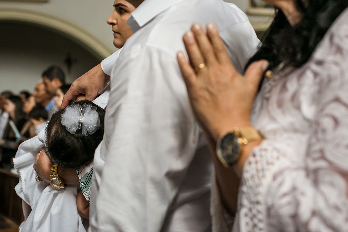 pais e padrinhos rezando durante a missa de batismo